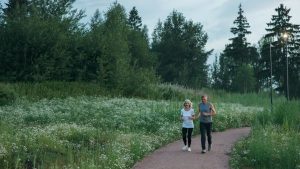 Senior couple jogging on a scenic park path surrounded by greenery.